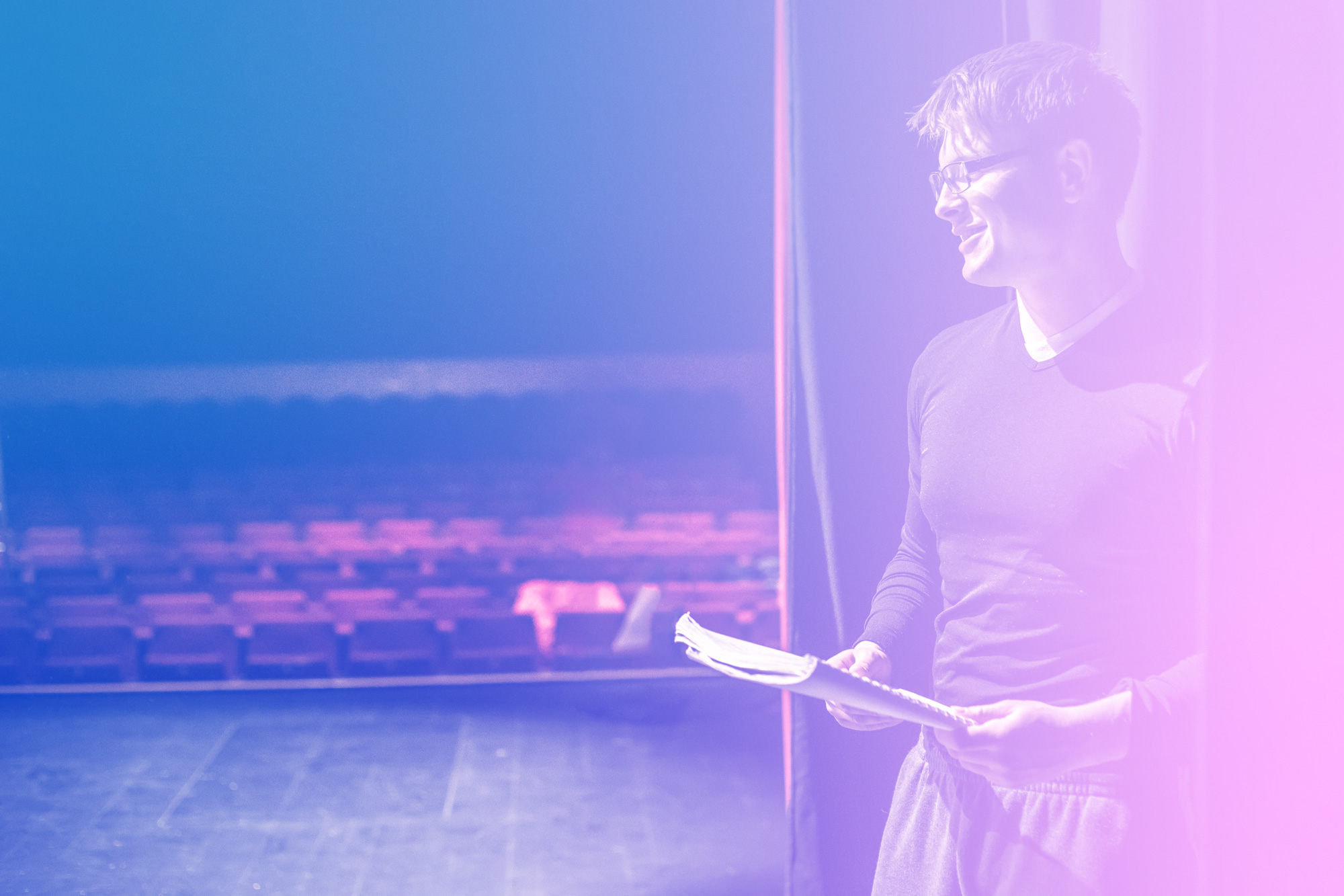 Background image showing a young actor during a theatre rehearsal